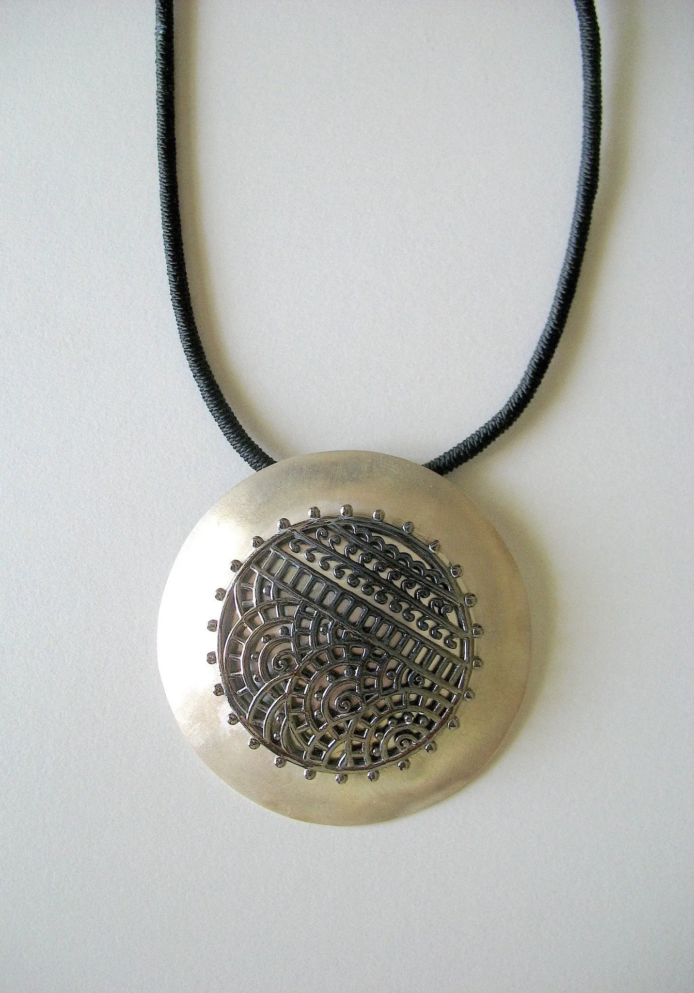 Dramatic, big round pendant with black rhodium plated mehndi-inspired center